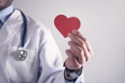 Doctor holding red paper heart. Healthcare and cardiology concept
