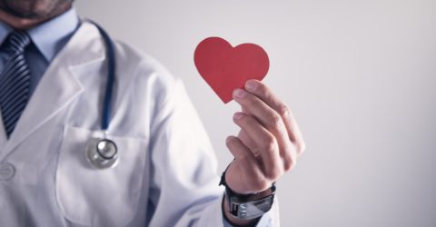 Doctor holding red paper heart. Healthcare and cardiology concept